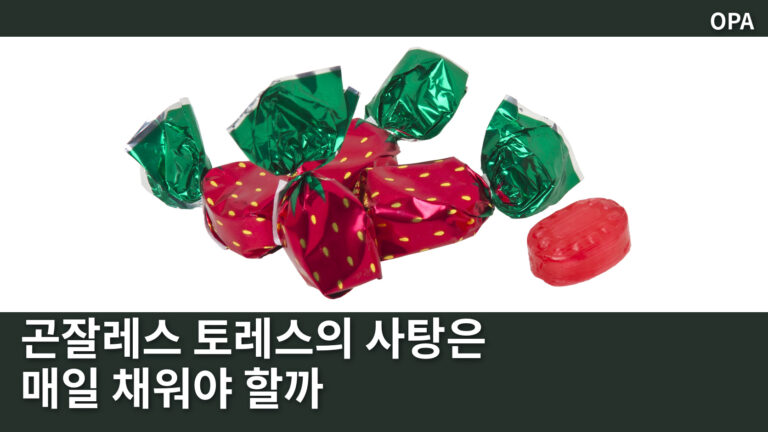 흰 바탕 위의 딸기무늬 포장 사탕 세 개와 포장을 벗긴 빨간 사탕 한 알