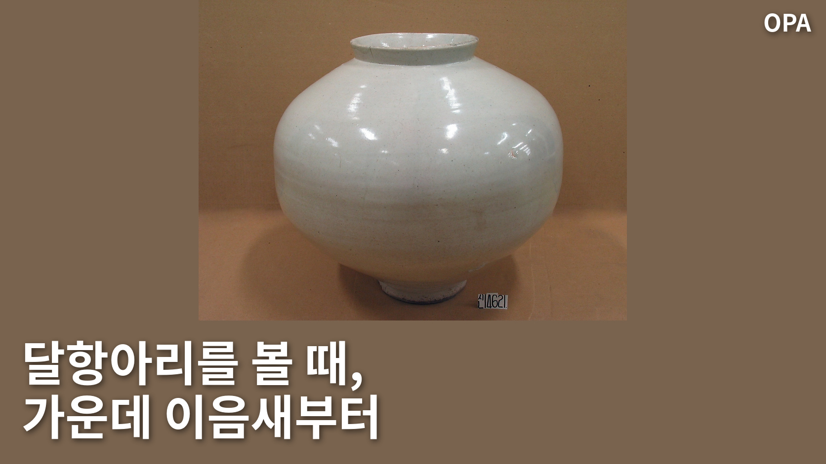 갈색 배경의 흰 달항아리. 입과 둥근 몸통, 굽, 오른쪽 아래 소장품 번호 표식이 보인다.