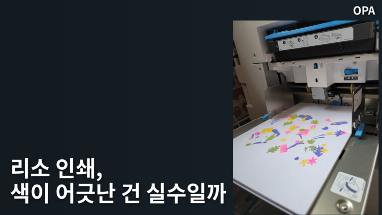 컬러 도형이 인쇄된 종이가 놓인 리소그래프 장비의 실제 모습. 리소 인쇄 공정을 보여 주는 참고 사진으로, 특정 스튜디오의 작품이나 색 어긋남의 의도를 증명하지 않는다.