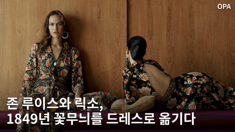 꽃무늬 의상을 입은 두 인물이 나무 벽 앞에 앉아 있는 모습